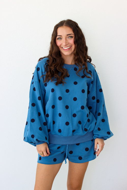 Woman wearing a blue sweater and shorts outfit set with black polka dots