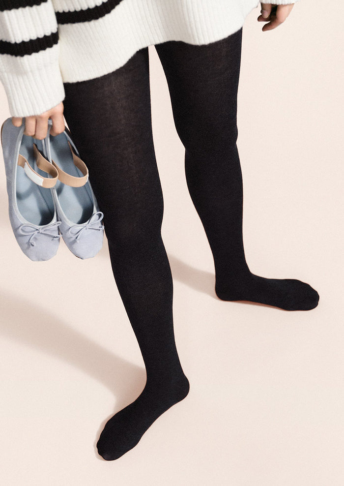 A person wearing knit tights in navy.