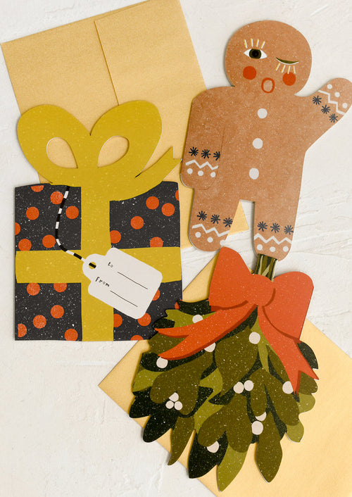 A set of die cut greeting cards in assortment of gingerbread man, wrapped present, and mistletoe shapes.