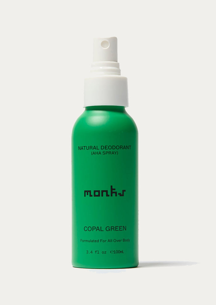 Green deodorant spray bottle with white cap on a white background
