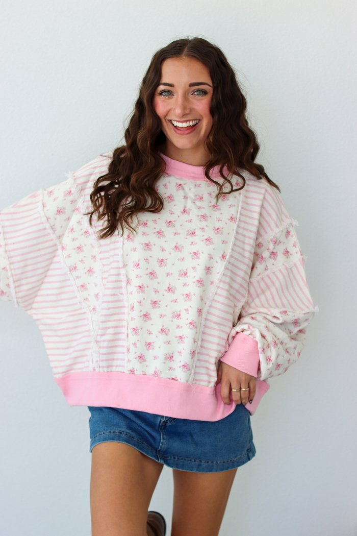 Woman wearing a pink patchwork distressed sweater with a blue denim mini skirt