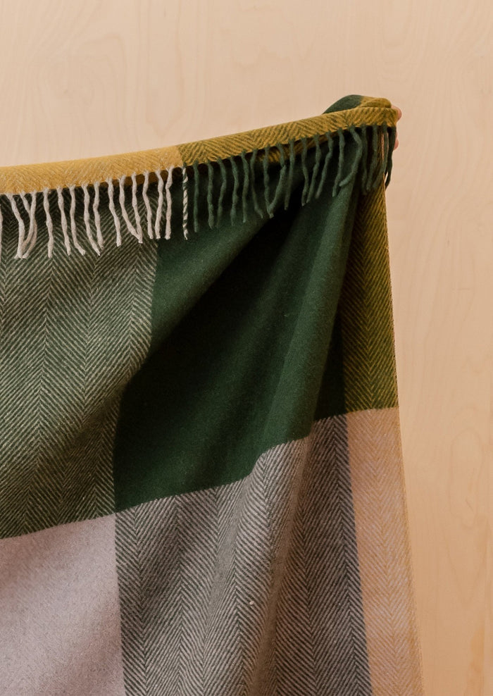 A throw blanket with colorful big check pattern in dark green, mustard and pink.