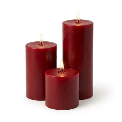 Three lit red pillar candles in assorted sizes on a white backdrop