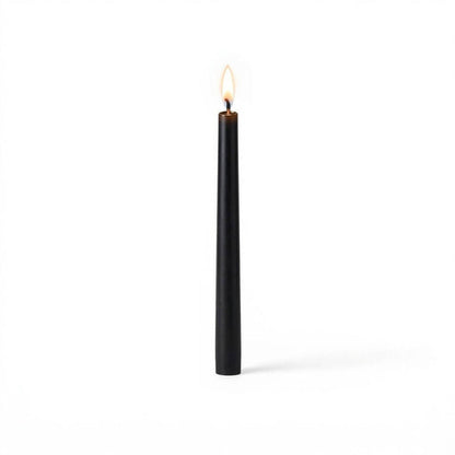 Black taper candle burning on white background