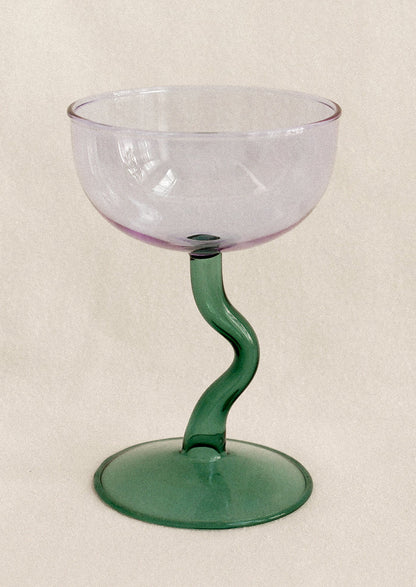 Glass with purple bowl and green stem on a beige background